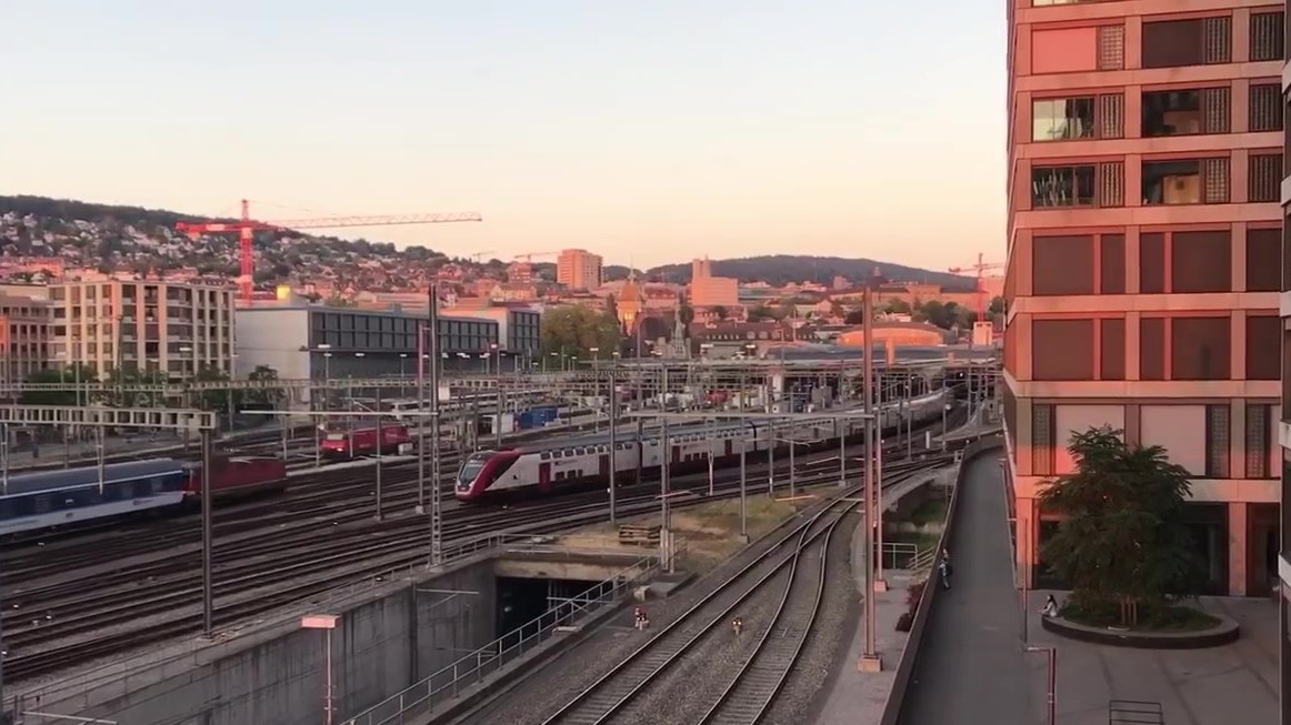 Trains entering and exiting a train station at sunset